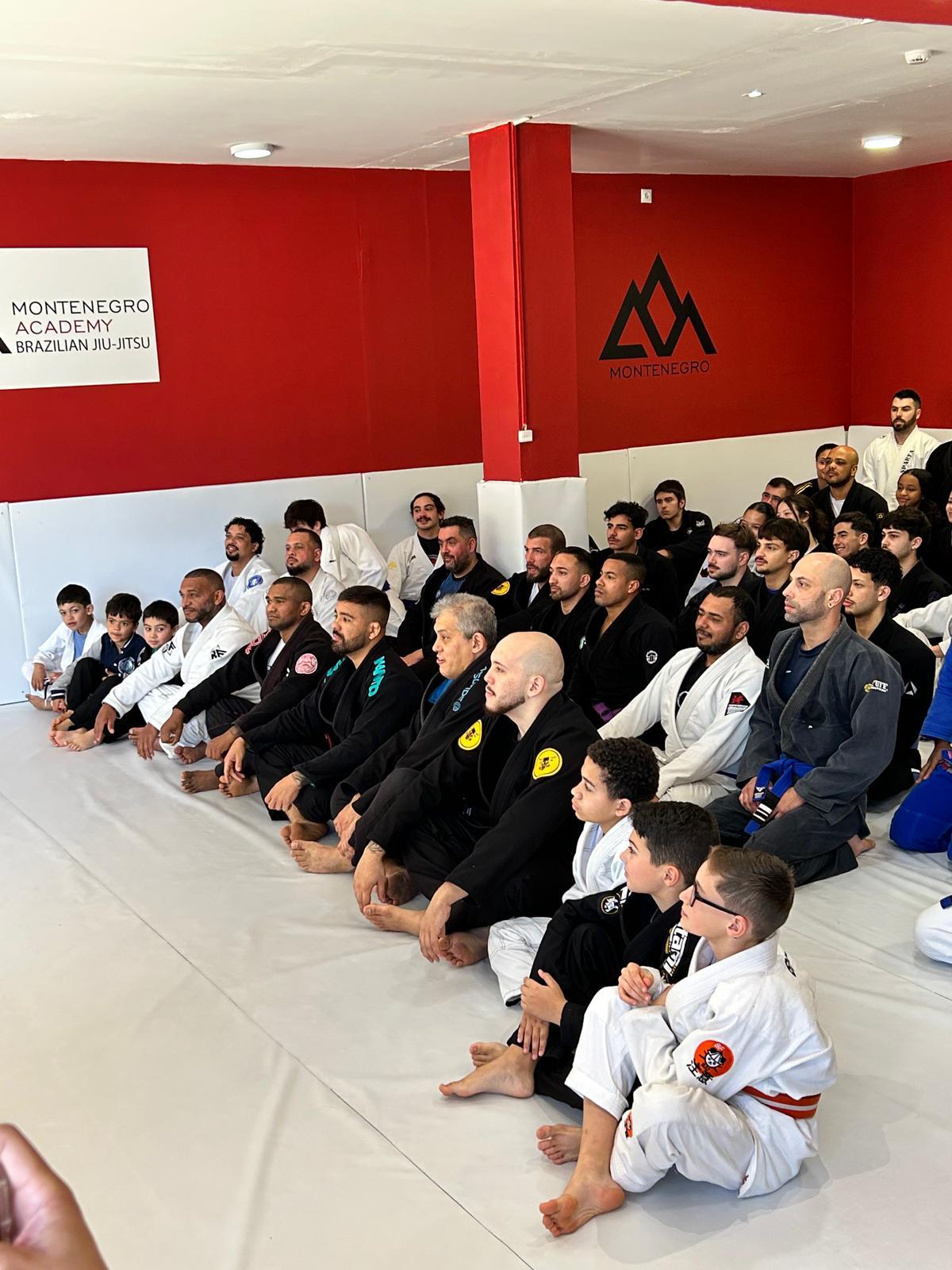 Turma da Montenegro Academy reunida no tatame, junto à parede com a marca da academia